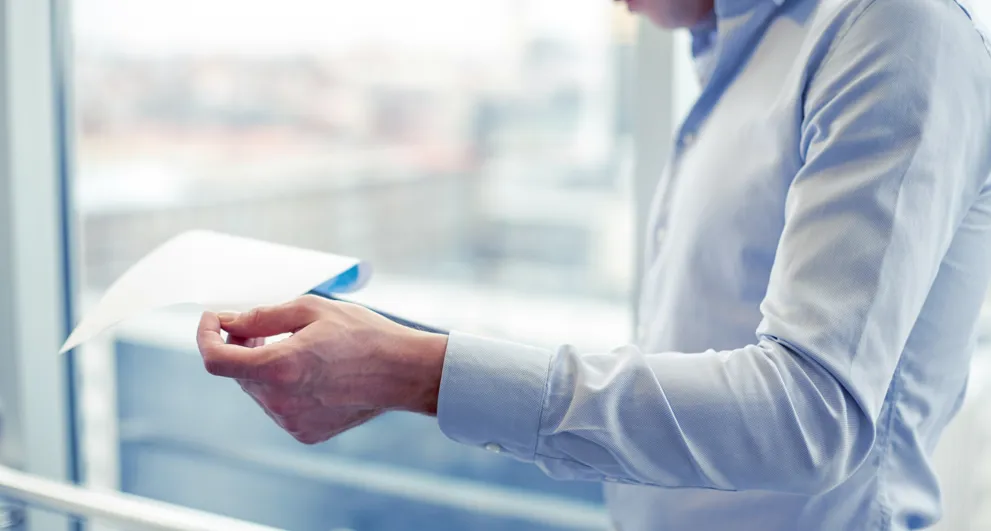 Businessman With Clipboard And Papers In Office